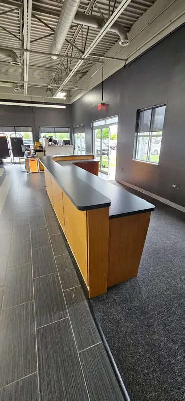 Installed dealership service counter with maple woodgrain laminate front and dark grey laminate top