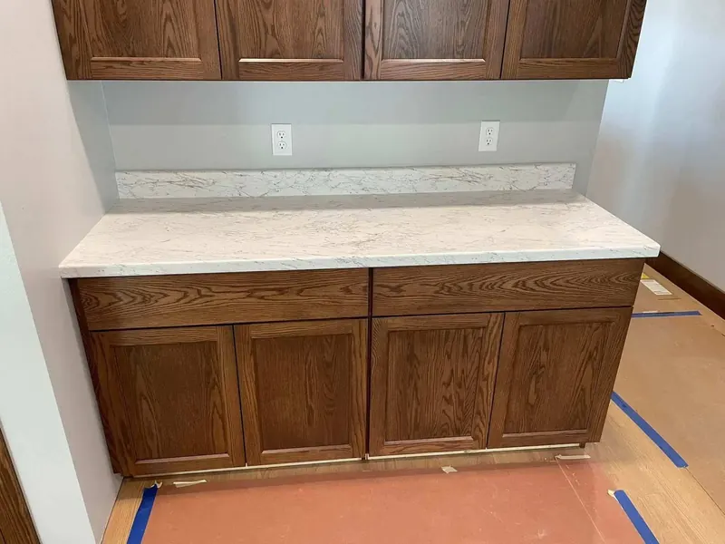 White marble-look laminate counter with matching backsplash on dark oak base cabinets