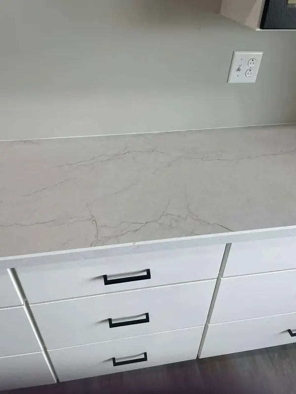 White marble-look laminate counter with fine grey veining over flat-panel white cabinets