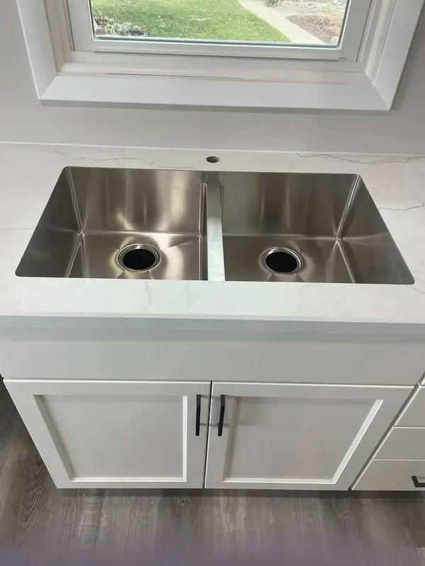 White marble-look laminate counter with a stainless double-bowl sink beneath a kitchen window