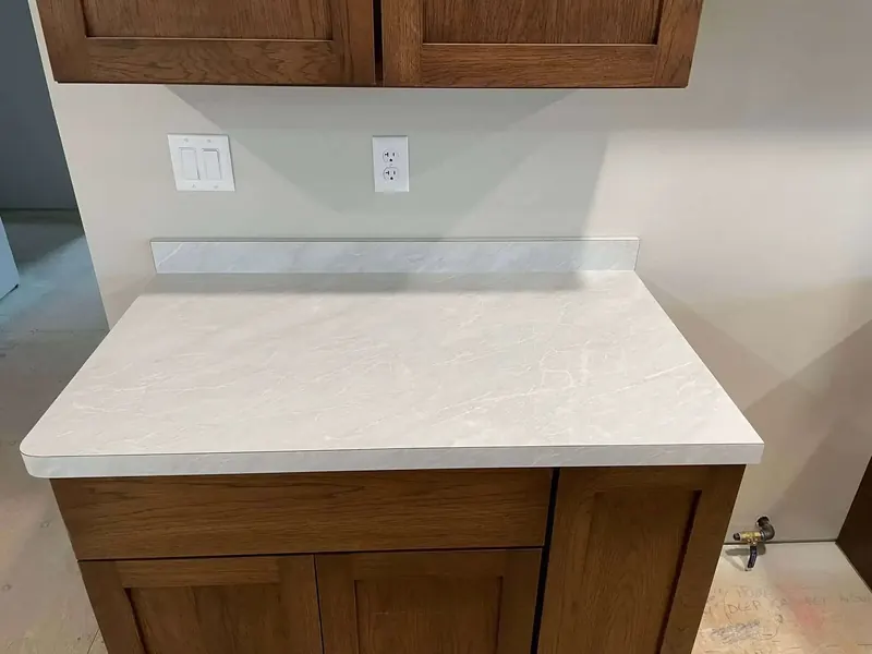 Cream stone-look laminate counter with matching backsplash on oak shaker cabinets