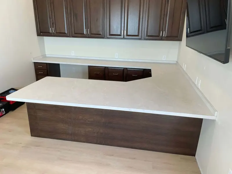 Large L-shaped kitchen peninsula in cream marbled laminate with dark wood cabinets