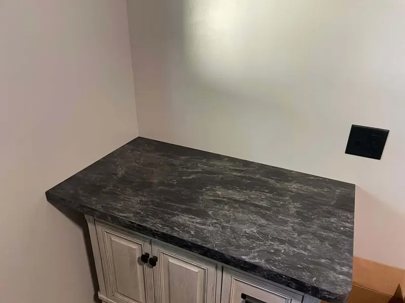Charcoal marbled laminate bar top on distressed white cabinetry
